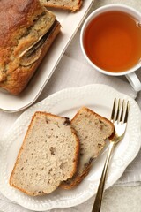Cut banana bread with nuts and tea on table, flat lay