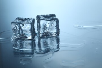 Cubes of clear ice on mirror surface, space for text
