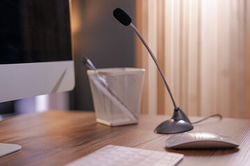 Microphone and computer on wooden desk indoors