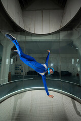 A man in overalls and a protective helmet enjoys flying in a wind tunnel. Free fall simulator