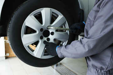 Mechanic changing tire at car service, closeup