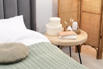 Side table with books and decor near bed indoors