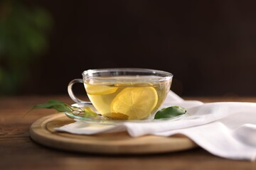 Cup of tasty green tea with lemon on wooden table, closeup