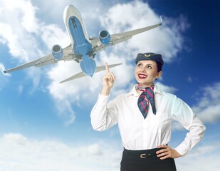 Smiling stewardess pointing at plane in blue sky with and clouds