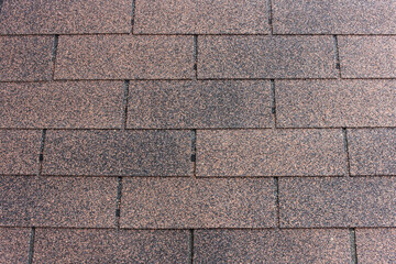 View of a residential roof covered in textured asphalt shingles, displaying a rich, aged redwood color.