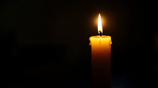 A single lit candle casting a warm glow in the darkness