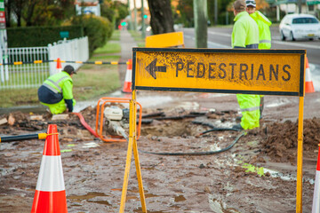 Dirty pedestrians this way sign and muddy road from broken water main