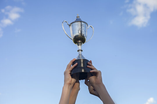 Teenage hands holding winning grand final trophy in the sky