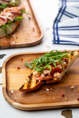 A beautifully arranged platter showcases a vibrant bruschetta topped with tomatoes, arugula, and savory toppings, highlighting a warm and inviting kitchen atmosphere