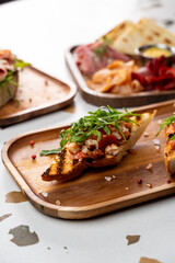 Freshly prepared bruschetta topped with colorful ingredients is served on charming wooden platters, inviting enjoyment in a warm, lively atmosphere filled with laughter