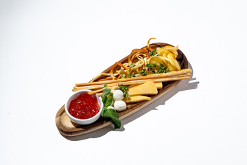 A beautifully arranged wooden platter showcases a selection of creamy cheeses and crunchy breadsticks, complemented by a bright red dip. Perfect for sharing at an intimate gathering or party