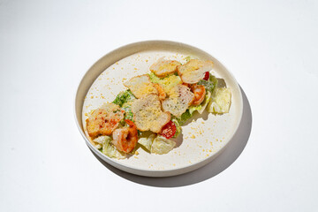 Fresh romaine lettuce and cherry tomatoes are beautifully arranged on a plate, topped with golden, crispy elements