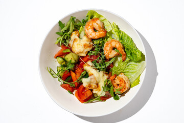 A colorful bowl filled with crunchy lettuce, ripe tomatoes, cucumbers, and perfectly grilled shrimp topped with melted cheese, creating an appetizing summer dish