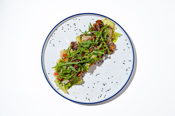 A healthy salad composed of crisp lettuce, vibrant vegetables, and a sprinkle of herbs sits beautifully on a white plate, exuding freshness and color under natural light