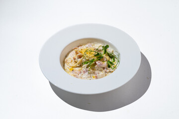 A tantalizing bowl of creamy pasta showcases tender noodles mixed with savory ingredients. Fresh herbs top the dish, enhancing its vibrant presentation in a bright, minimalist setting