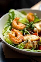 A delightful bowl filled with crisp lettuce, juicy shrimp, and colorful vegetables showcases a culinary creation. The dish emanates freshness, ideal for a light meal in a modern eatery