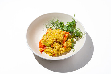 Creamy risotto filled with colorful vegetables and vibrant herbs sits elegantly on a clean white surface, showcasing an inviting meal that's perfect for any dining occasion