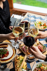Friends gather around a beautifully set table, toasting with glasses of red and white wine. Plates filled with gourmet dishes are shared, creating a warm ambiance of joy and culinary delight