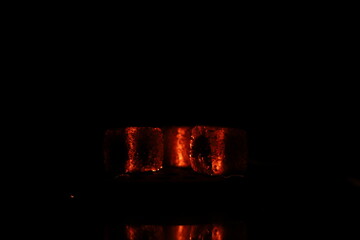 Glowing coals with glitch style lighting, enriched by noise, effect and grain details, create a mystical atmosphere in the dark. A vivid sense of heat and depth surrounds the image