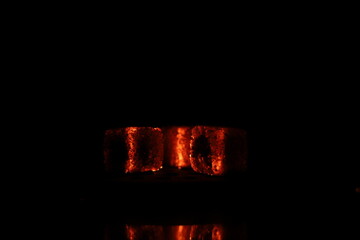 Glowing coals with glitch style lighting, enriched by noise, effect and grain details, create a mystical atmosphere in the dark. A vivid sense of heat and depth surrounds the image