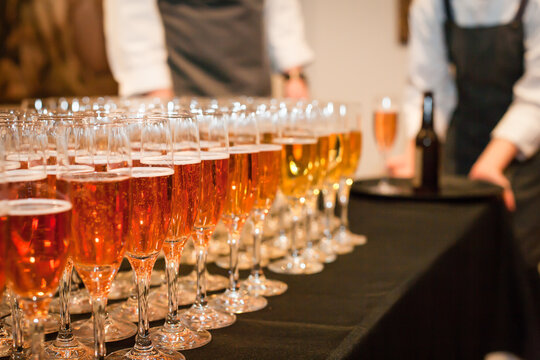 Row of glasses with sparkling wine and waiters in background