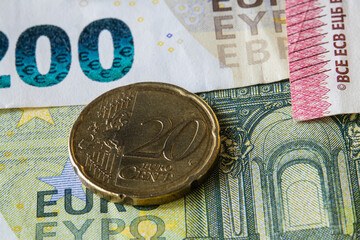 Close-up of a 20 euro cent coin placed on a 200 euro banknote.