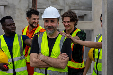 Group of engineers from different cultures stands behind his senior supervisor to support his...