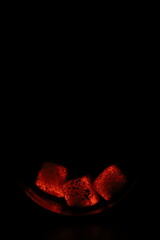 Glowing coals with glitch style lighting, enriched by noise, effect and grain details, create a mystical atmosphere in the dark. A vivid sense of heat and depth surrounds the image