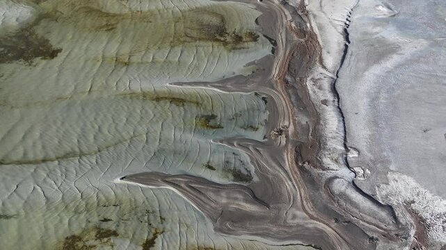 Aerial Great Salt Lake mud shore environment above 1. Largest saltwater lake in the Western Hemisphere. Solar evaporation ponds produce salt, potassium, magnesium. Recreation and industry.