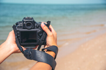 Man traveler using digital camera on summer beach blue sky take a photo. Asian Photographer man...