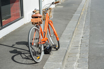 A ladies bicycle leaning against a pole on the footpath