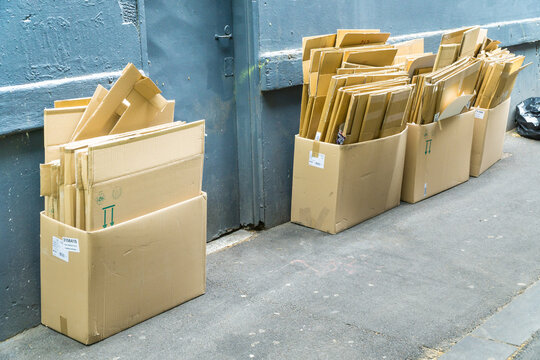 Boxes of cardboard stacked outside against a wall in an alley