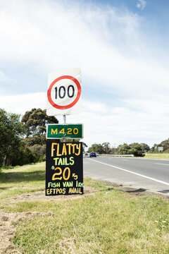 Orange and yellow roadside sign advertising flathead tails vertical