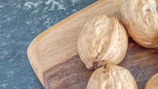 Close up view of walnuts on a wooden board with a marbled blue surface as a background in a studio shot
