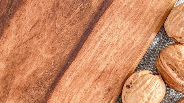Close up of walnuts on a gray cloth next to a wooden board with a diagonal shadow across it
