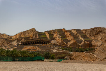 building with arches nestles against terraced rocky slopes