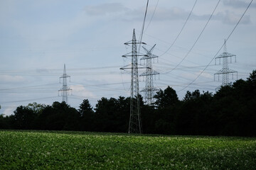 A field with a tall power line tower in the middle