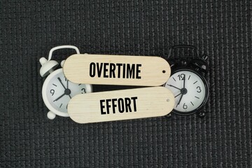 Two alarm clocks with the words Overtime effort. Overtime work concept.