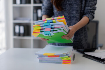 Close up of hands working in Stacks of paper files for searching and checking unfinished document...