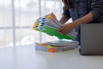 Close up of hands working in Stacks of paper files for searching and checking unfinished document...
