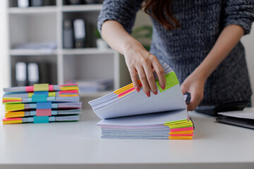 Close up of hands working in Stacks of paper files for searching and checking unfinished document...