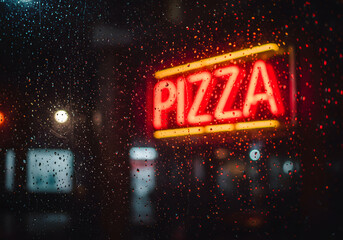 Rain streaked pizza neon sign nighttime
