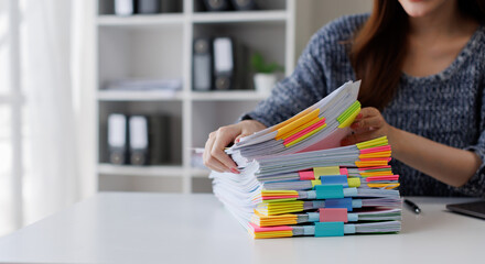 Business Documents, Business woman working in Stacks of paper files for searching and checking...