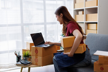 Happy asian business sme entrepreneur owner is smiling while taking notes in her office full of...