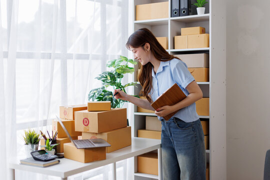 Asian woman entrepreneur taking notes while working on laptop a customer managing orders in her sme small business store. sme supply chain, procurement, omnichannel or coronavirus quarantine concept.
 - Powered by Adobe