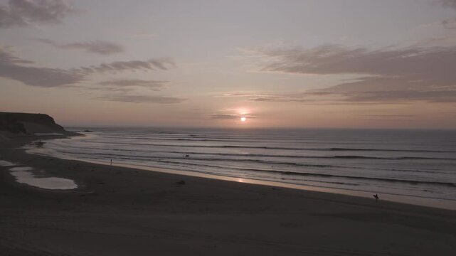a sunset shot of a surfer walking along the beach at the el point section of chicama, the world's longest lefthand point break at puerto malabrigo, peru
