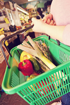 woman with a basketful of fruit and veg at a greengrocer