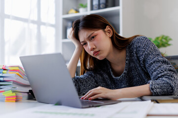 Young asian woman accountant employee Upset stressed guy suffering job problems working on laptop,...