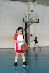 basketball by asian child or kid girl fun playing and training to learning bouncing and raising ball with children at sports stadium school or basketball court gymnasium for exercise on sport day