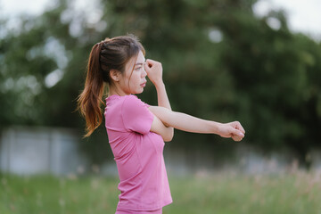 
A young woman in pink athletic wear pauses, seemingly catching her breath after exercise, looking...